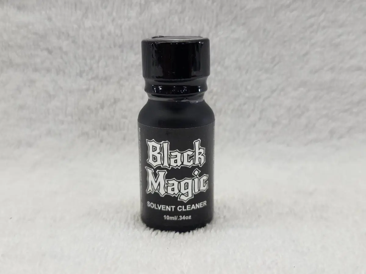 A bottle of black magic on a white surface.