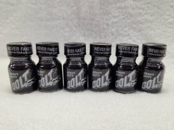 Five bottles of black liquid with a white label on them.