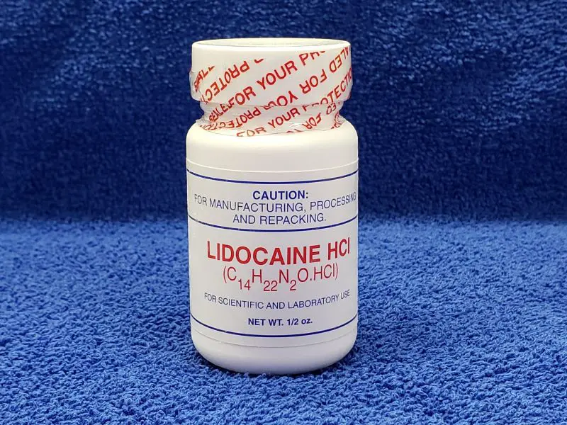 A bottle of lidocaine hcl on a blue towel.