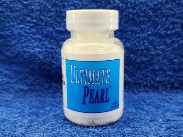 A bottle of ultimate pearl is sitting on the ground.