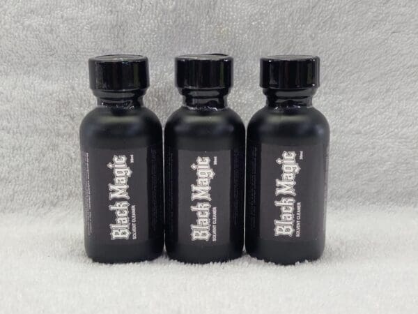 Three black magic bottles sitting on a white surface.