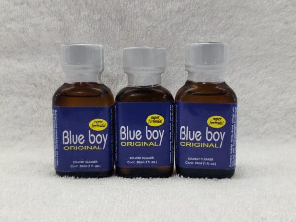 Three bottles of blue boy cough syrup on a table.