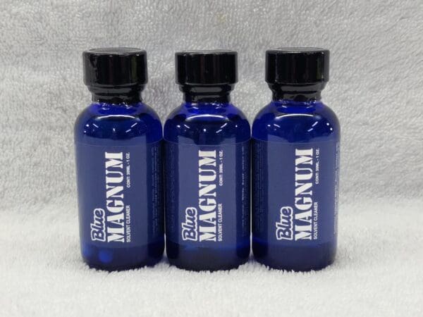 Three blue bottles of liquid with black caps.