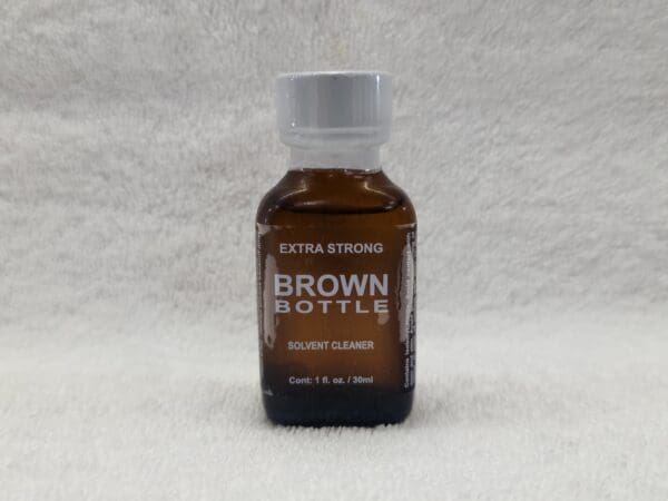 A bottle of brown liquid on top of a white table.