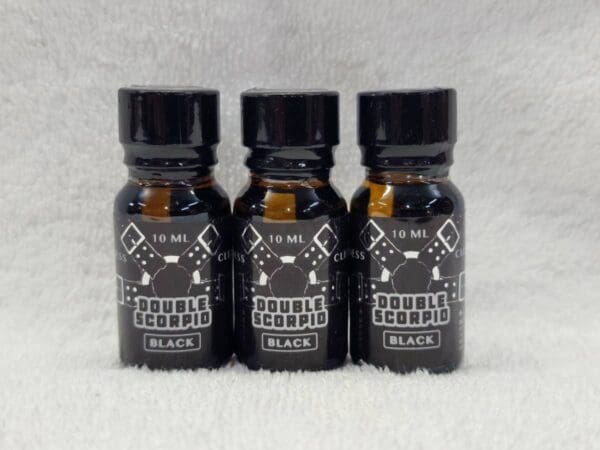 Three bottles of black e - liquid on a white background.