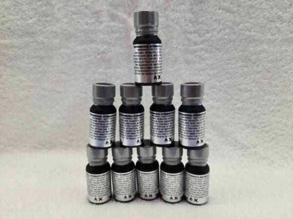 A stack of six bottles of black oil on a white background.