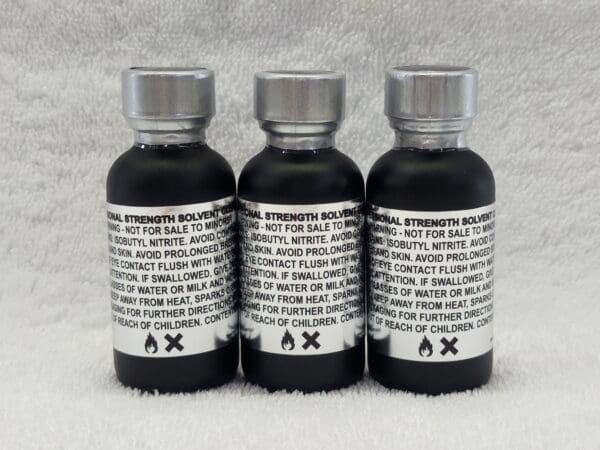 Three bottles of black liquid on a white background