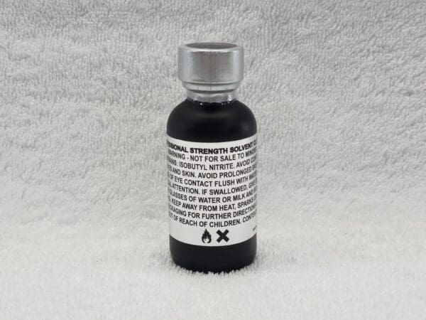 A bottle of black liquid sitting on top of a white surface.