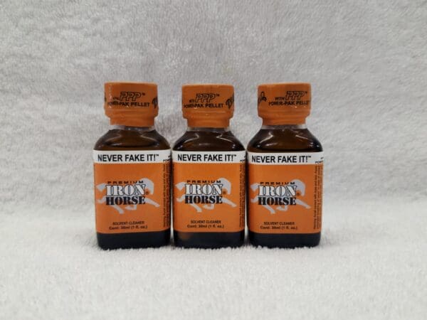 Three bottles of orange poppers on a white background