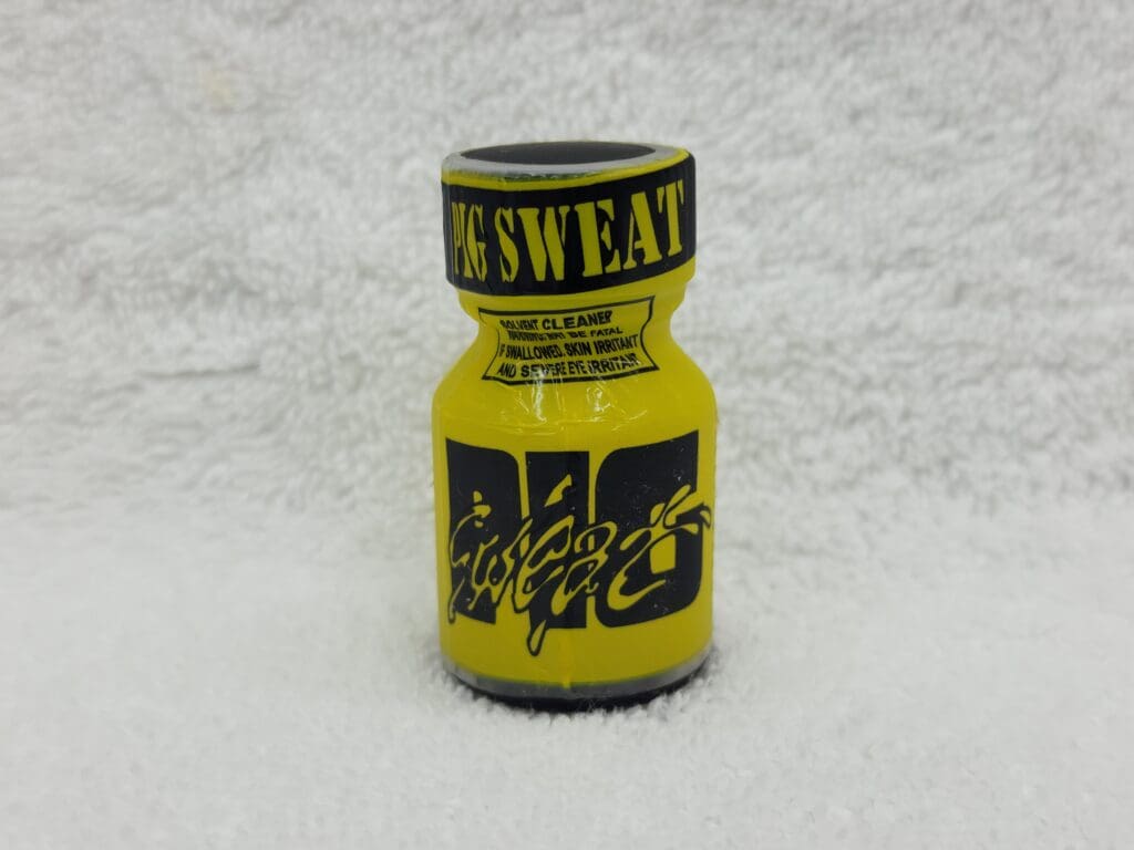 A yellow bottle of poppers on top of a white blanket.