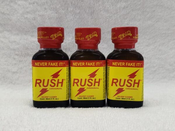 Three bottles of rush poppers on a table.