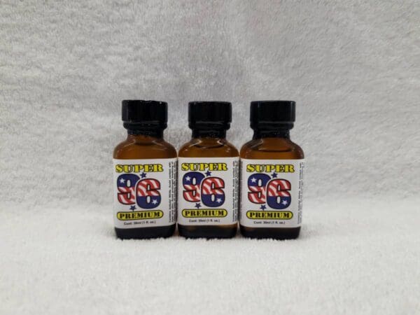 Three bottles of oil sitting on top of a white sheet.