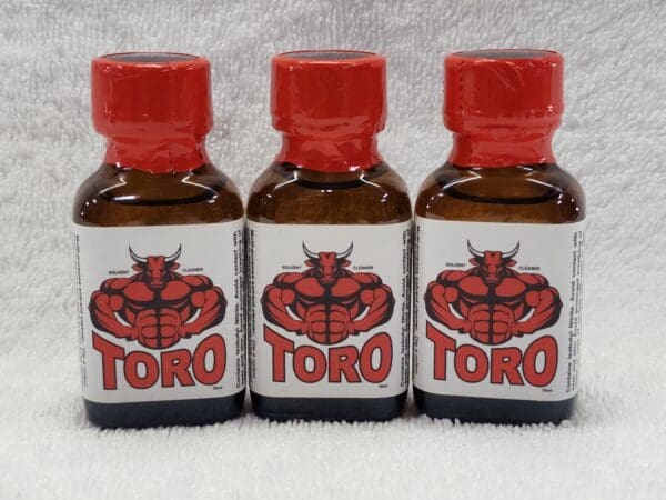 Three bottles of toro poppers sitting on a white surface.