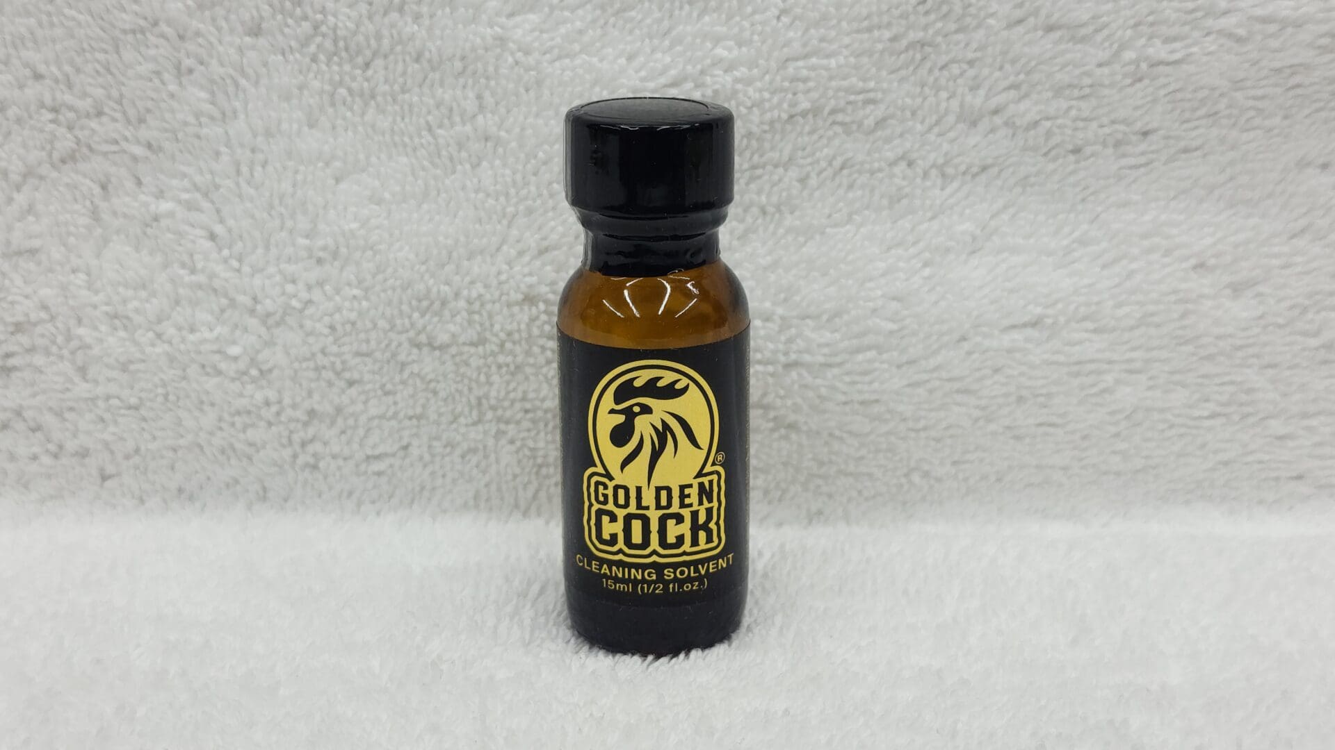A bottle of Golden Cock Original cleaning solvent, 2 fl oz size, on a white textured background.