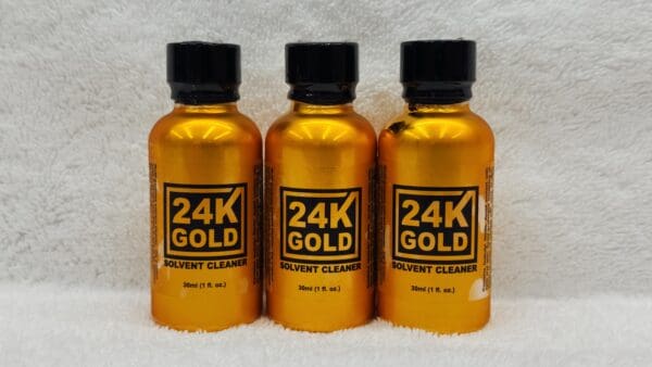 Three bottles labeled "24K Gold" on a white towel, showcasing identical content and design.