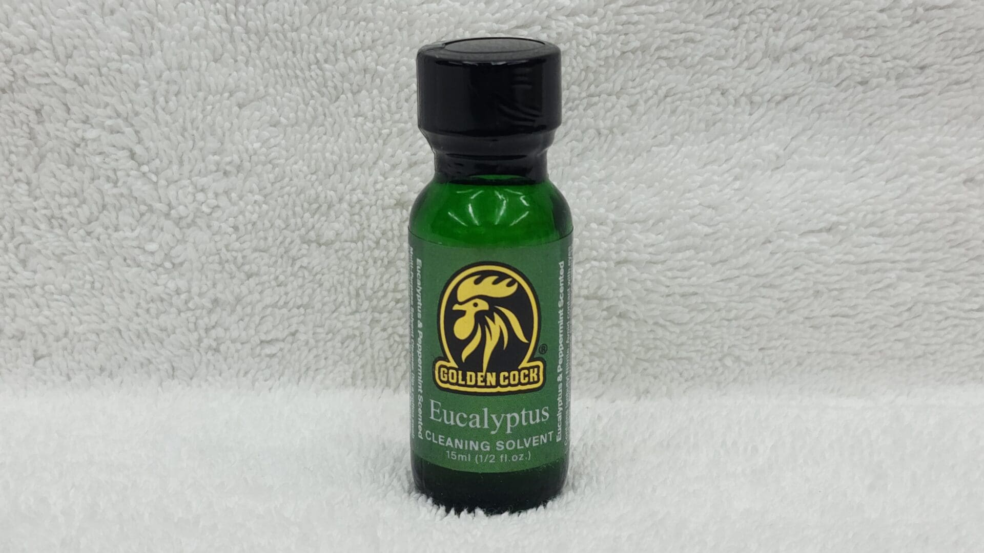 A small bottle of Golden Cock Eucalyptus cleaning solvent on a white towel.