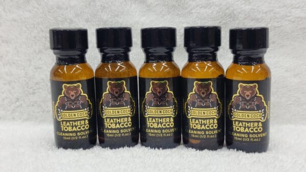 Five bottles of Golden Cock Leather & Tobacco cleaning solvent on a white fluffy surface, each containing 15ml (0.5 oz).