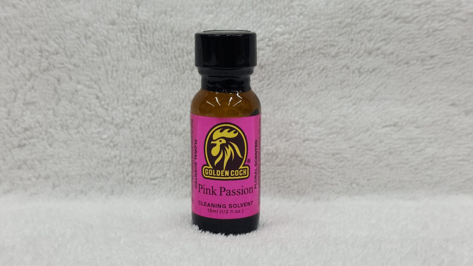 A bottle labeled "Golden Cock Pink Passion" (1 fl oz) on a white towel background.