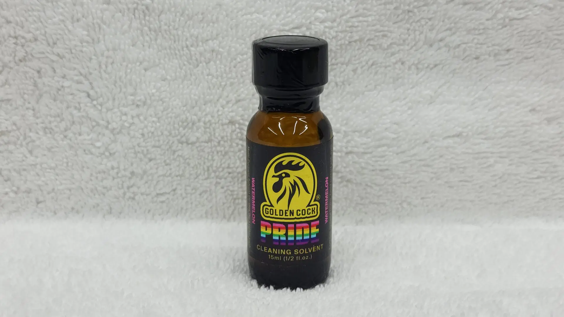 A small bottle labeled "Golden Cock Pride" on a white textured background.