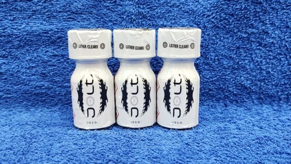 Three bottles of Jolt Coconut cleaning solution with black and white labels, arranged side by side on a blue textured background.