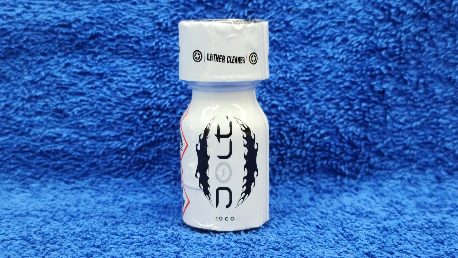 A small white bottle of Jolt Coconut cleaner labeled "loco" with a black and red dragon graphic, on a blue textured background.