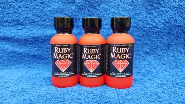 Three bottles of Ruby Magic hair dye on a blue towel background.