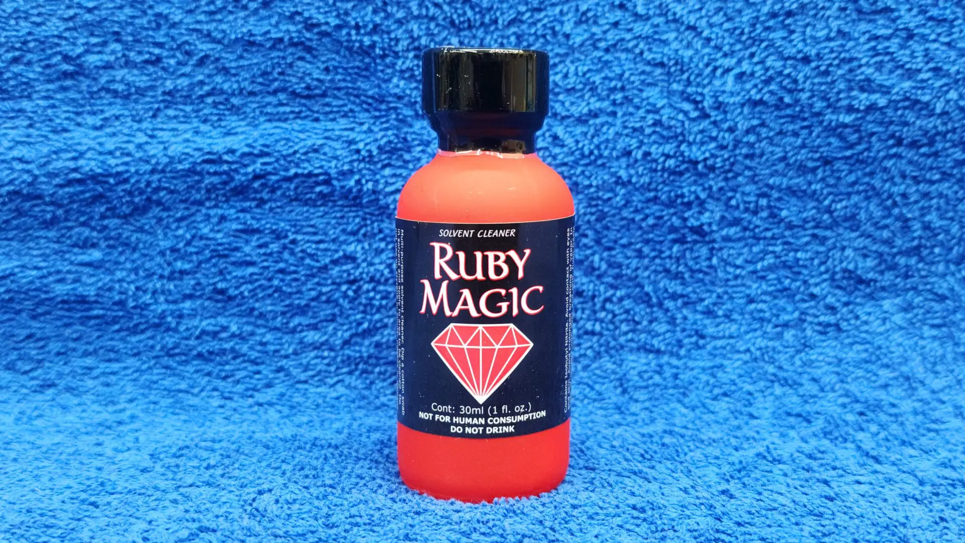 A bottle of Ruby Magic beverage on a blue textured background.