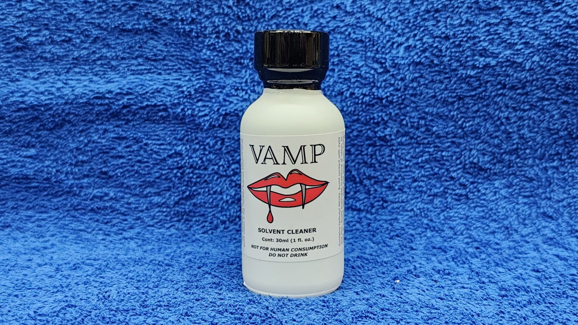 A bottle of Vamp solvent cleaner with a graphic of red lips on a blue towel background.