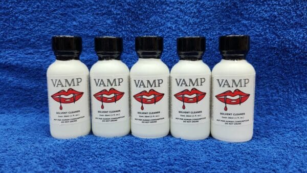 Five white bottles labeled "Ruby Magic" with red lips logo, aligned on a blue textured background.